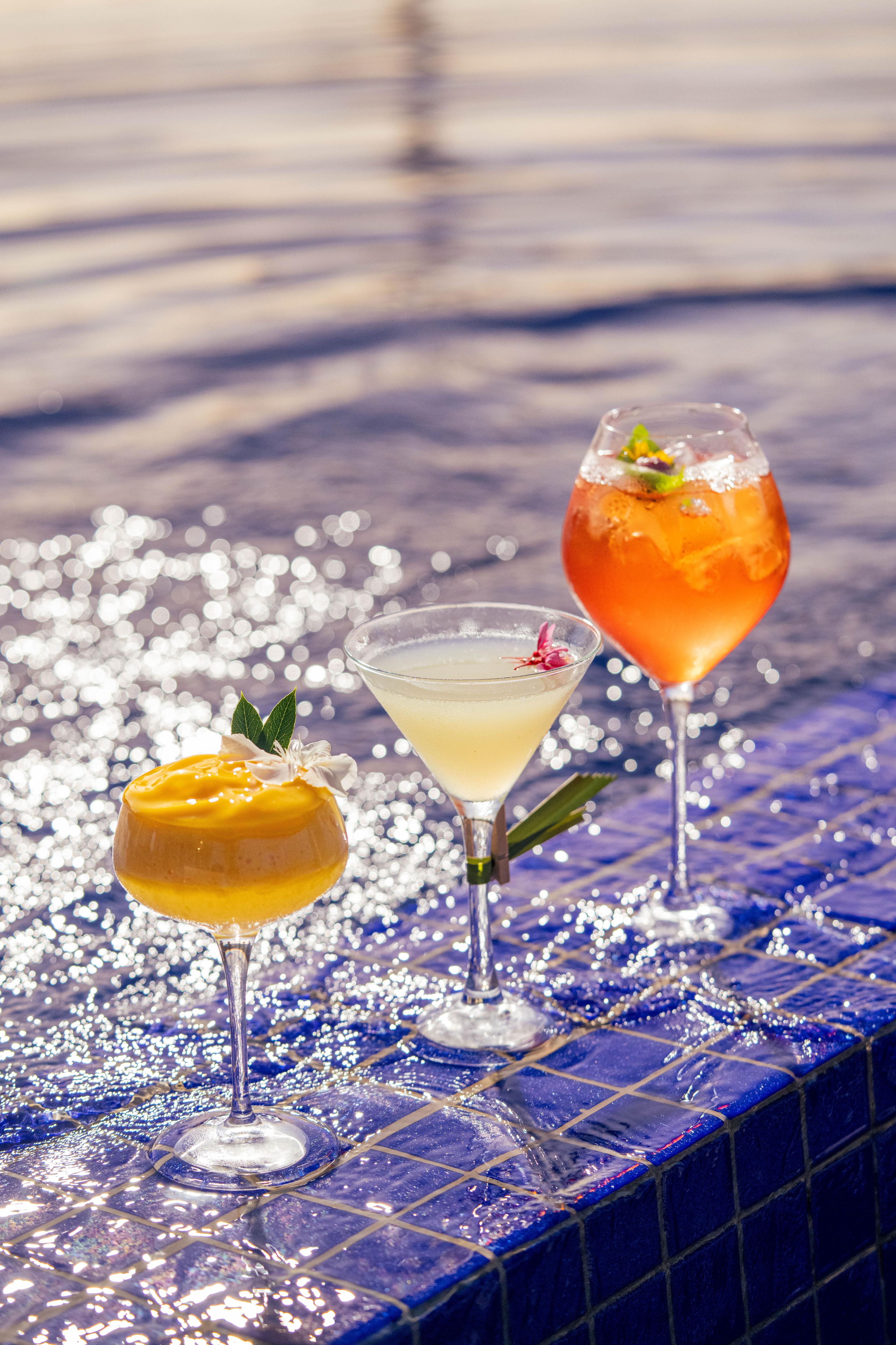 Cocktails set on poolside, sparkling in sunlight at Banyan Tree Tamouda Bay Buddha Bar beach rooftop.